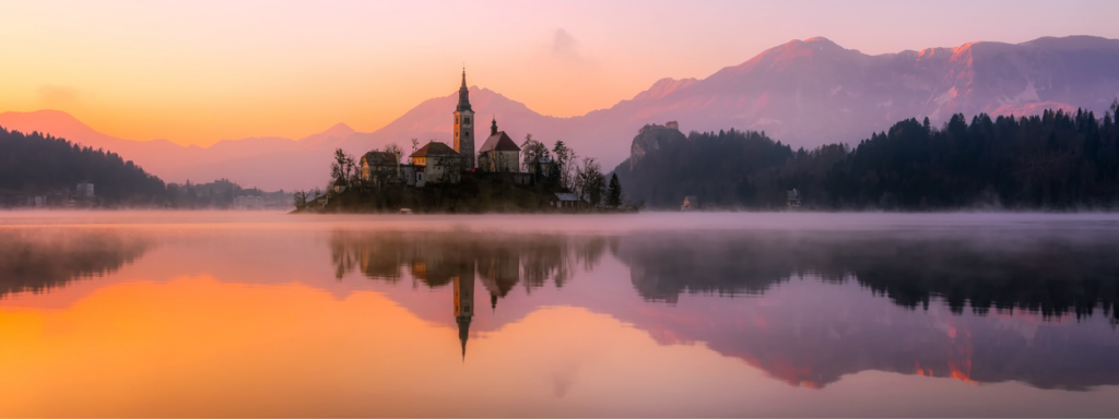 church sunset purple and orange over a lake at dusk